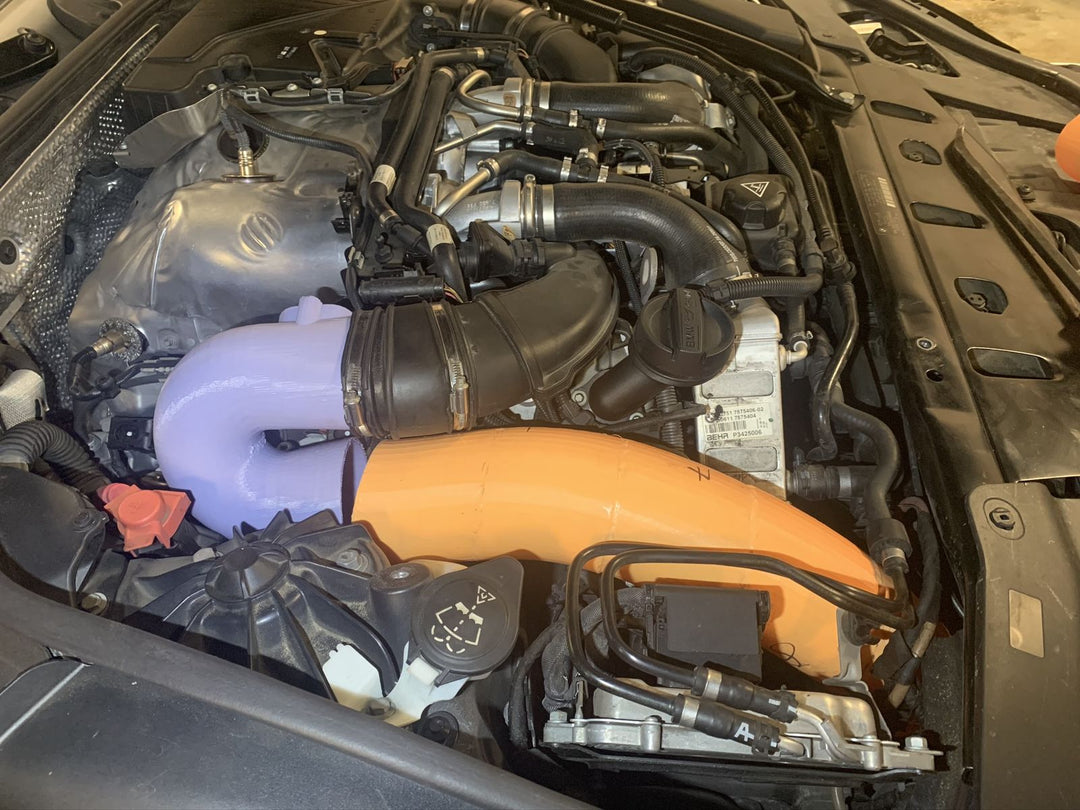 An early Project Gamma development car: a BMW engine bay with a lilac silicone intake tube and an orange silicone charge pipe fitted alongside the factory hardware.