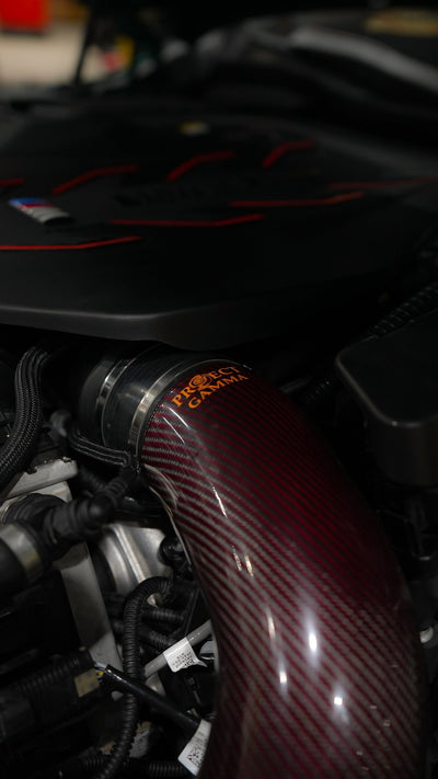 Close-up of a Project Gamma carbon fiber intake installed on a BMW M5 G90