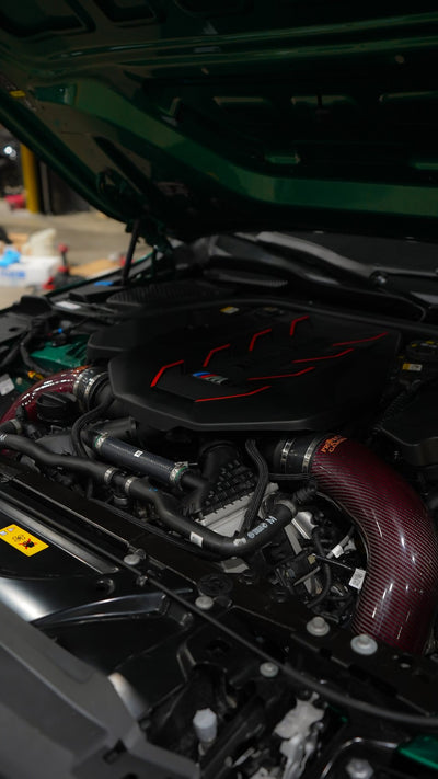 Engine bay of a BMW M5 G90 with Project Gamma carbon fiber intakes installed