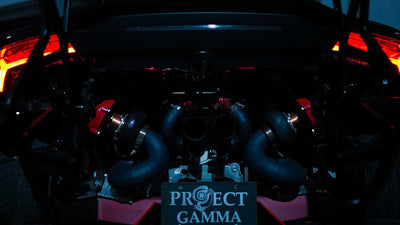 Close view of the twin turbochargers and manifolds of a Project Gamma twin turbo kit in a black Lamborghini Huracán