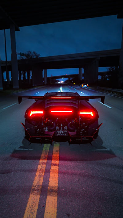 Black Lamborghini Huracán at night with its tail lights lit and the twin turbo setup exposed under the rear glass