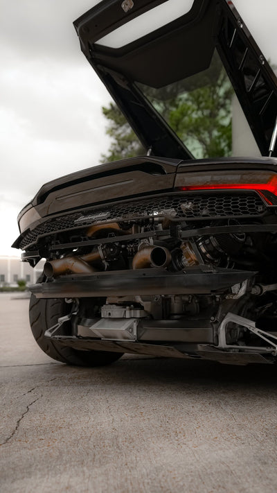 Rear of a black Lamborghini Huracán with the bumper removed, showing the twin turbo exhaust