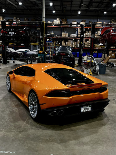 Orange Lamborghini Huracán in the workshop, rear three-quarter view