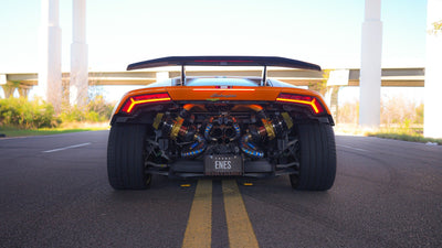 Orange Lamborghini Huracán seen straight from the rear, twin turbochargers and exhaust exposed beneath the wing