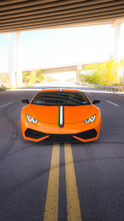 Orange Lamborghini Huracán with a large rear wing, photographed head-on on the road